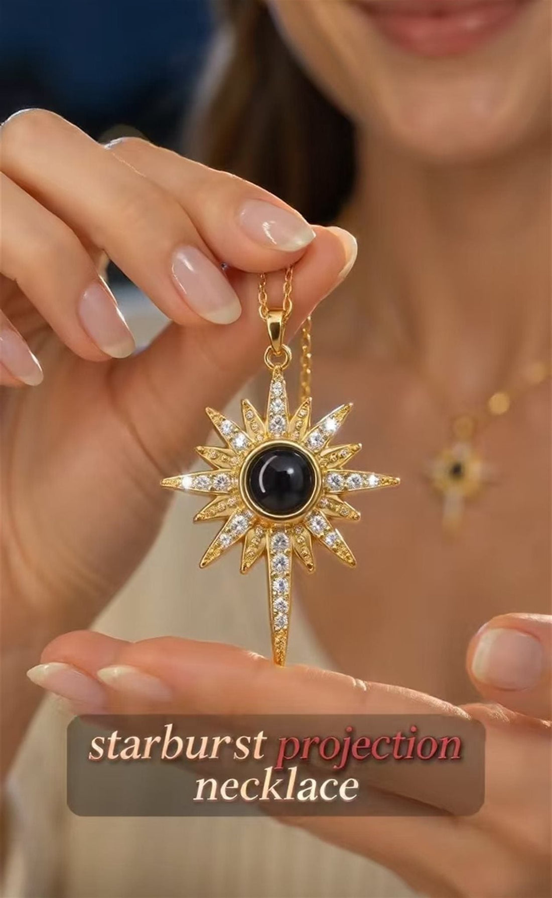 Gold-tone starburst projection necklace with a dark central lens and sparkling accents held by its chain